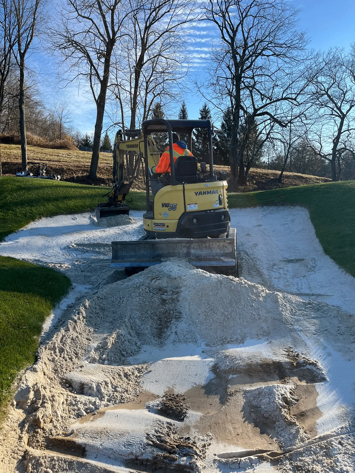 Mini excavator reshaping a bunker with fresh sand