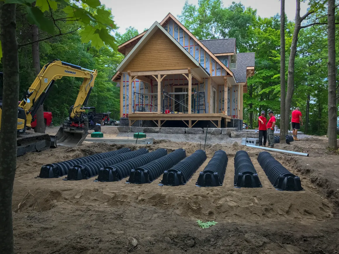 New home construction site with excavator and septic field installation