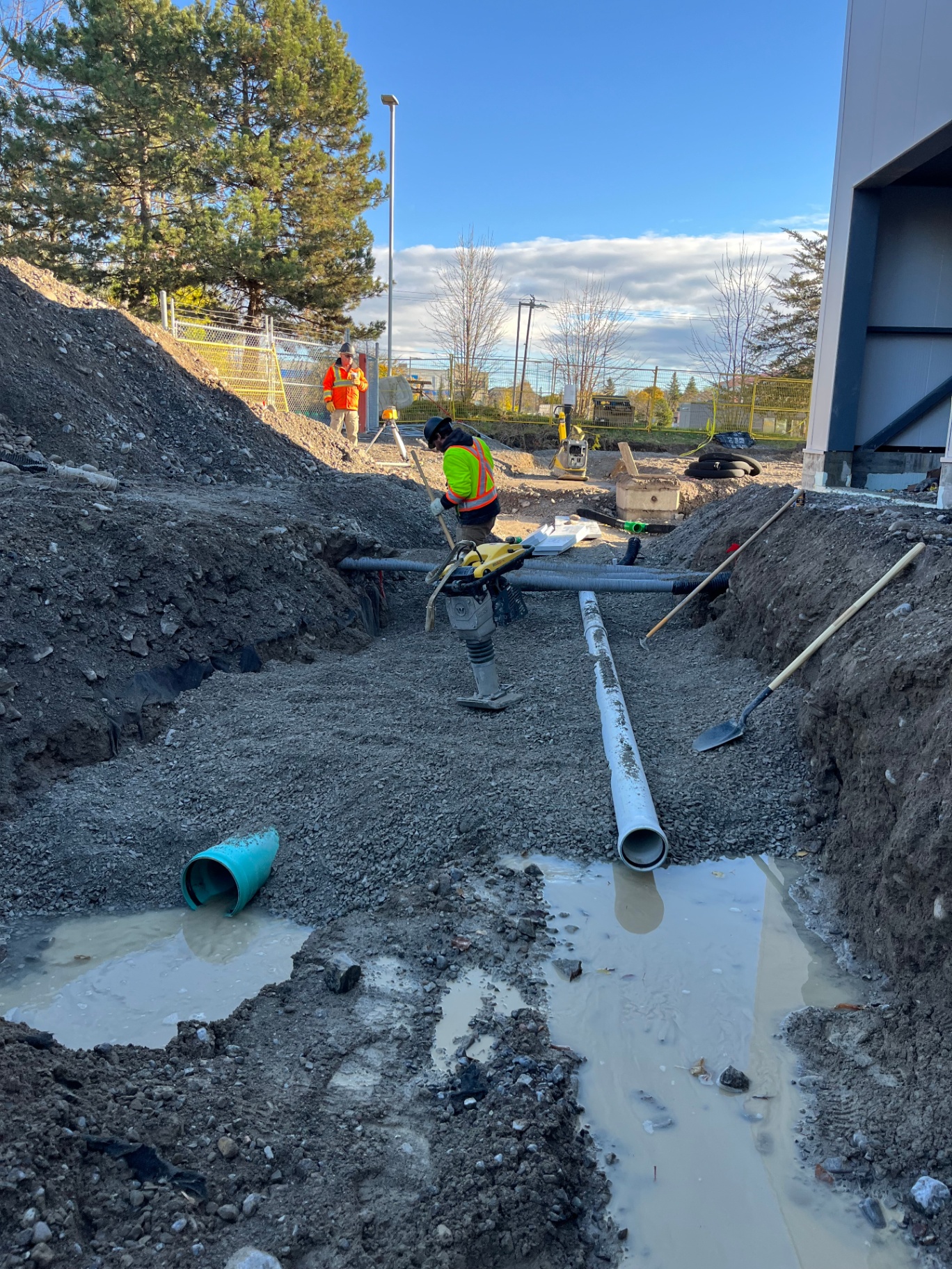 Crew installing site servicing trench at a commercial project